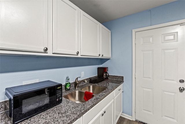 kitchen with white cabinetry, sink, dark stone countertops, and dark hardwood / wood-style floors