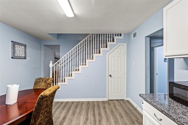 dining area featuring a textured ceiling and light wood-type flooring