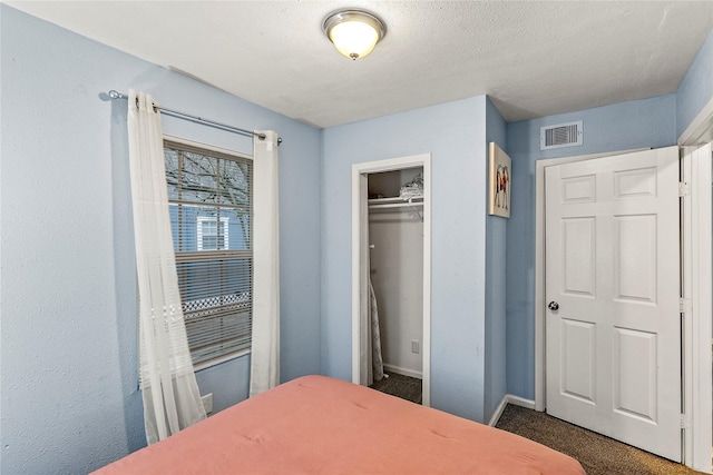 carpeted bedroom featuring a textured ceiling and a closet