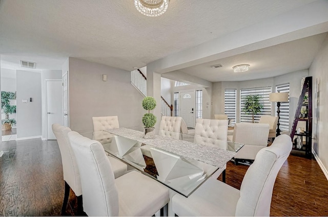 dining room with wood finished floors, visible vents, a textured ceiling, and baseboards