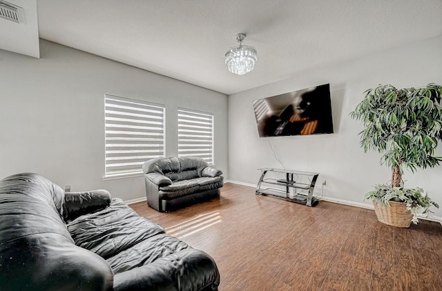 living room with a chandelier, wood finished floors, visible vents, and baseboards