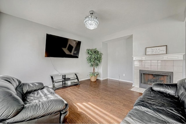 living area featuring wood finished floors, a tiled fireplace, and baseboards