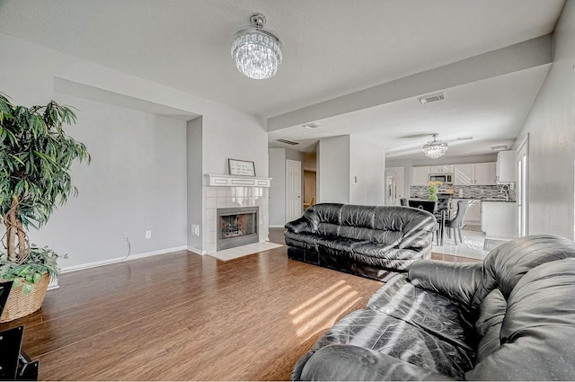 living area with a fireplace, visible vents, light wood-type flooring, and a notable chandelier