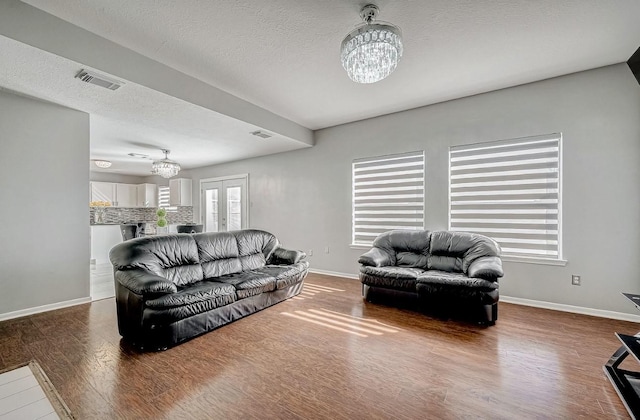living area featuring baseboards, visible vents, wood finished floors, and a notable chandelier