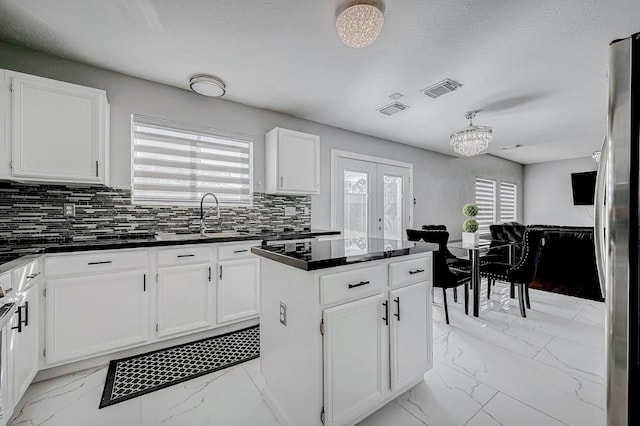 kitchen with decorative backsplash, marble finish floor, white cabinets, dark countertops, and visible vents