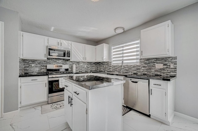kitchen with dark countertops, stainless steel appliances, marble finish floor, and a sink