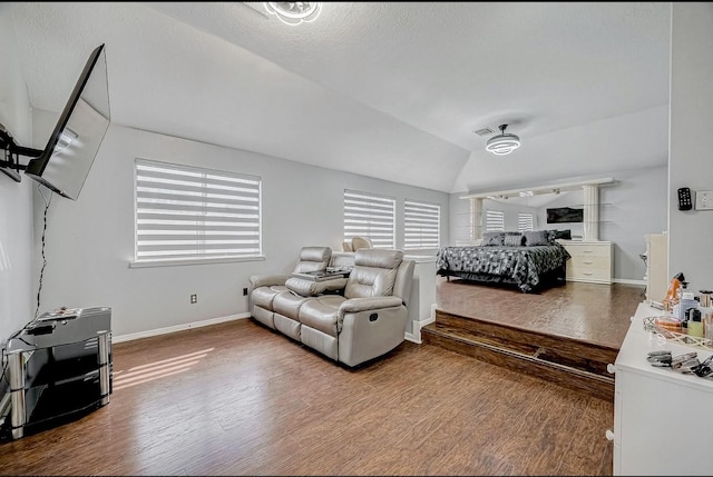 bedroom featuring baseboards, wood finished floors, and lofted ceiling