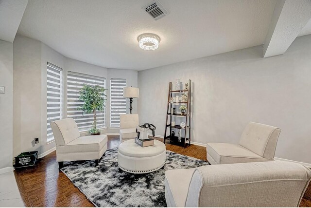 living area featuring baseboards, visible vents, wood finished floors, and a textured ceiling