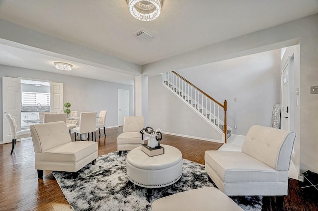 living room with stairs, visible vents, baseboards, and dark wood finished floors