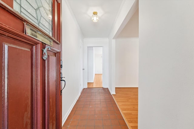 hallway featuring ornamental molding and dark tile patterned flooring