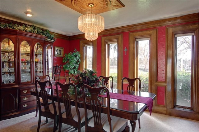 dining area with ornamental molding, carpet flooring, and a chandelier