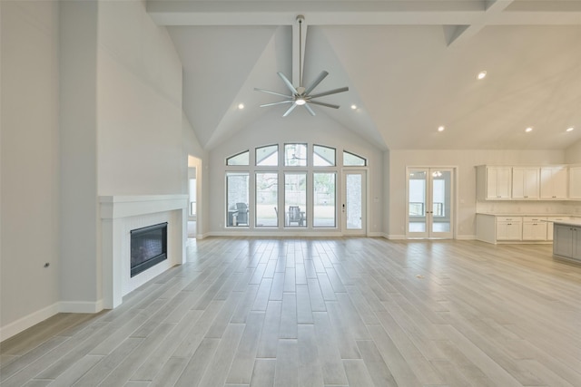 unfurnished living room featuring high vaulted ceiling, light wood finished floors, beam ceiling, and a healthy amount of sunlight