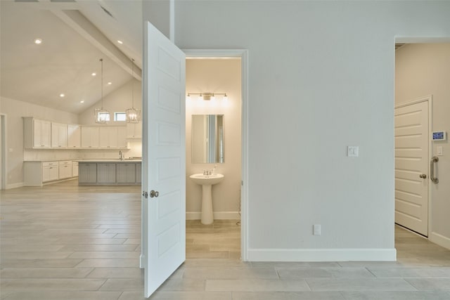 interior space featuring a sink, beam ceiling, baseboards, and wood finished floors