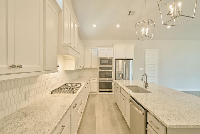 kitchen featuring stainless steel appliances, a sink, decorative light fixtures, and white cabinets