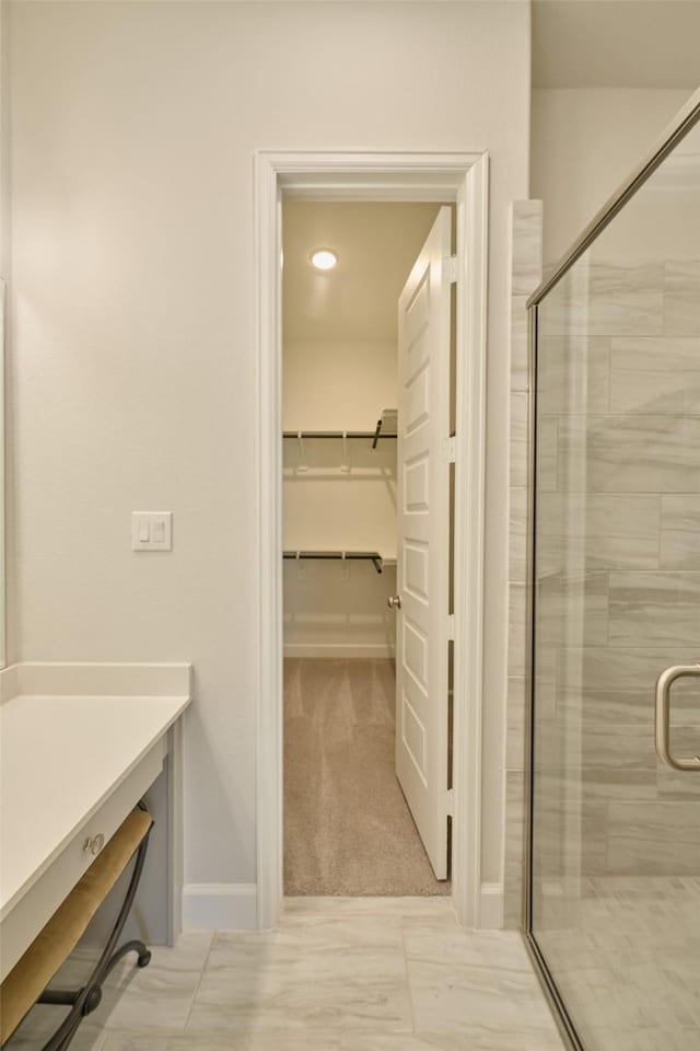 bathroom featuring a walk in closet, vanity, and a shower stall