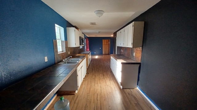 kitchen with white cabinetry, sink, and tile counters