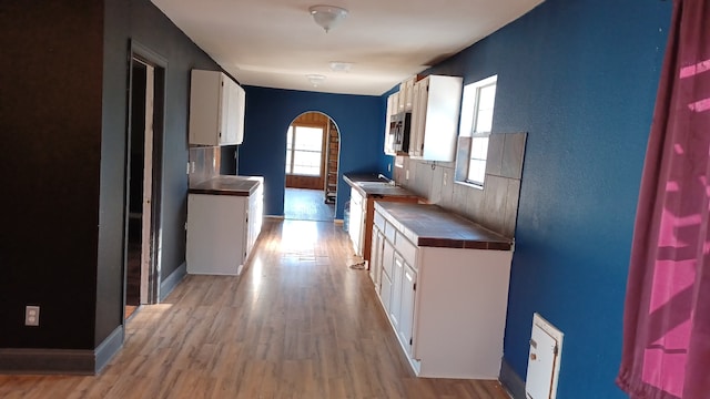 kitchen featuring light hardwood / wood-style flooring, tile counters, and white cabinets