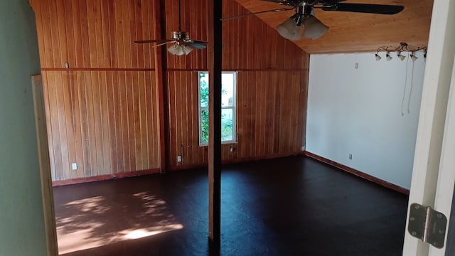 empty room with lofted ceiling, ceiling fan, and wood walls