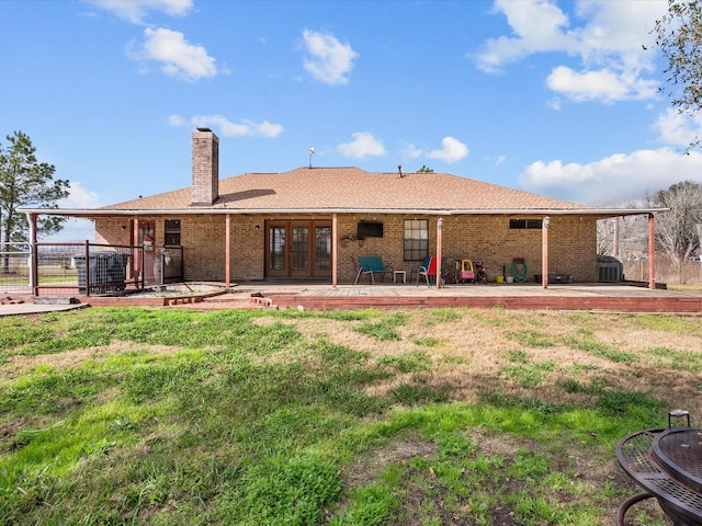 back of property with french doors, brick siding, fence, and a chimney