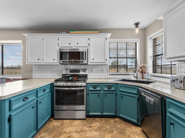 kitchen featuring a peninsula, white cabinetry, appliances with stainless steel finishes, and a sink