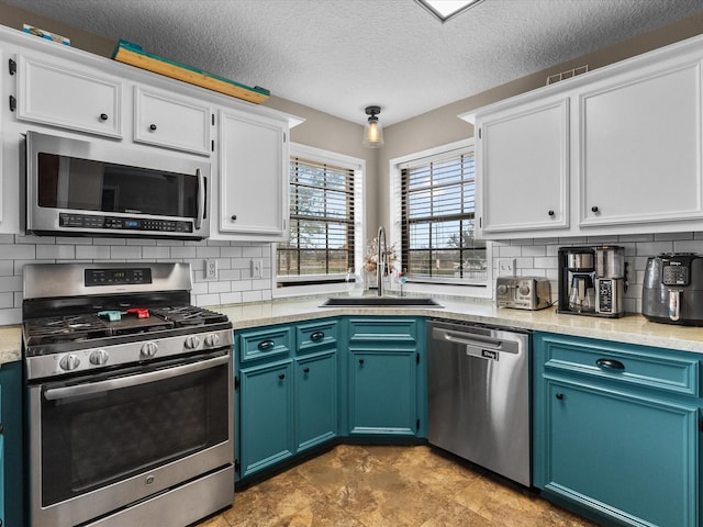 kitchen featuring stainless steel appliances, light countertops, backsplash, white cabinets, and a sink