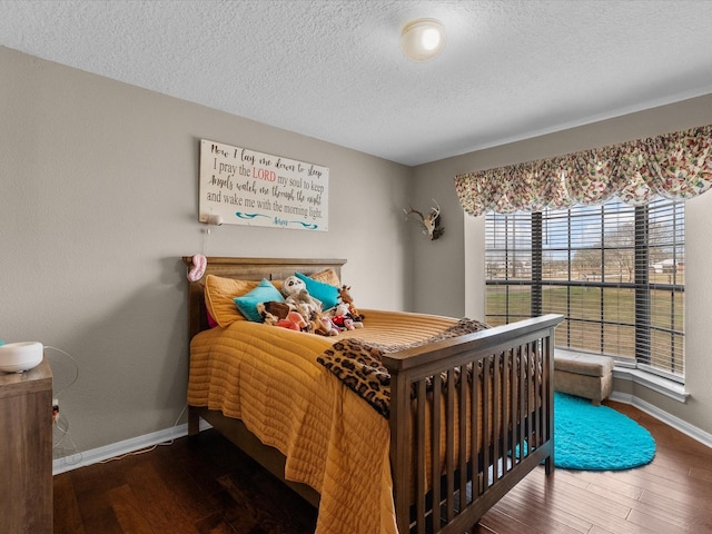 bedroom with a textured ceiling, baseboards, and hardwood / wood-style flooring