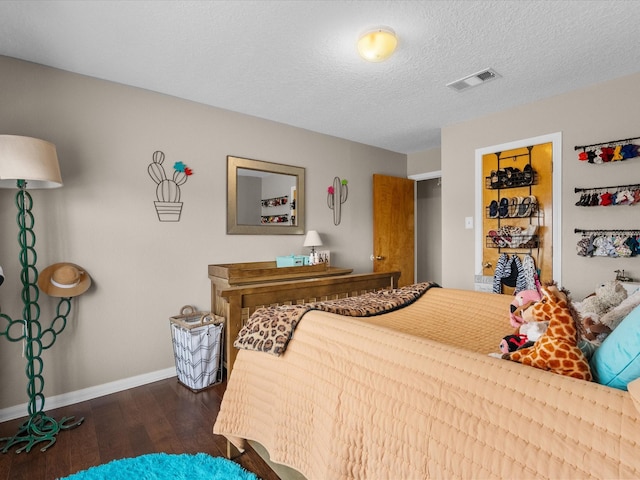 bedroom featuring baseboards, a textured ceiling, visible vents, and dark wood-style flooring