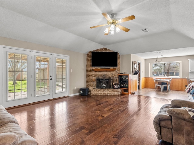 living room featuring lofted ceiling, visible vents, a ceiling fan, a textured ceiling, and wood finished floors