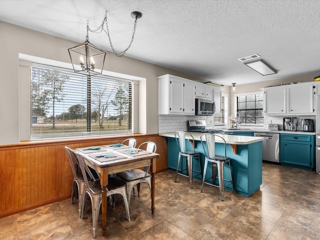 kitchen with stainless steel appliances, white cabinetry, a sink, and a peninsula