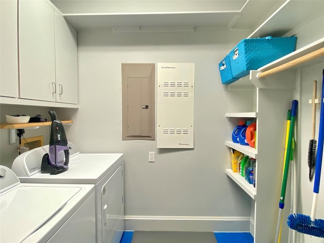 washroom with electric panel, washing machine and dryer, and cabinets