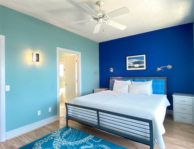 bedroom with light wood-type flooring, ensuite bath, ceiling fan, and a textured ceiling