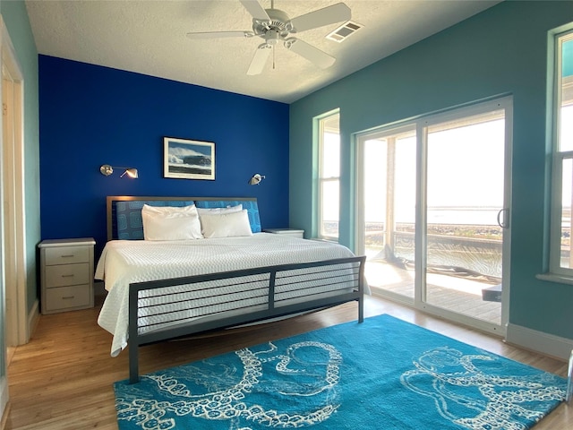 bedroom featuring ceiling fan, wood-type flooring, access to exterior, and a textured ceiling