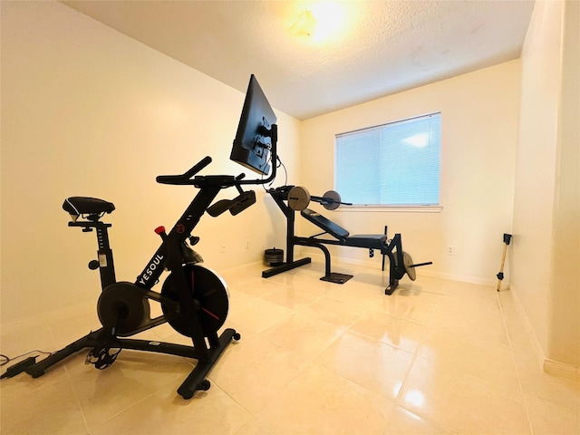 exercise area with tile patterned flooring and a textured ceiling