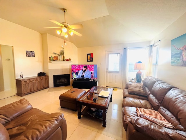 living room with light tile patterned floors, vaulted ceiling, a tile fireplace, and ceiling fan