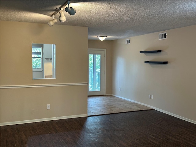 unfurnished room featuring a textured ceiling, a wealth of natural light, and wood-type flooring