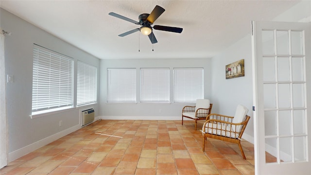 sitting room featuring ceiling fan, a wall mounted air conditioner, and light tile patterned floors