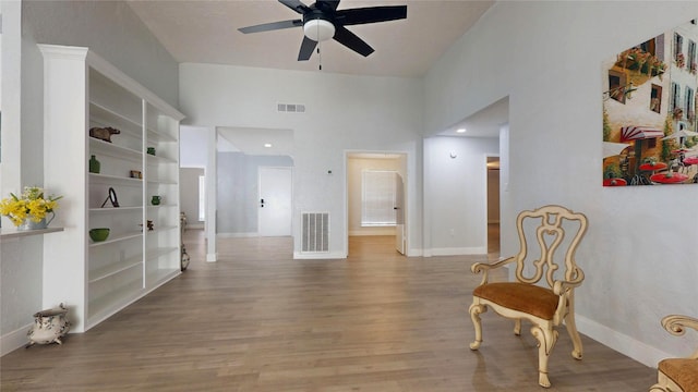 sitting room with ceiling fan, hardwood / wood-style floors, and a high ceiling