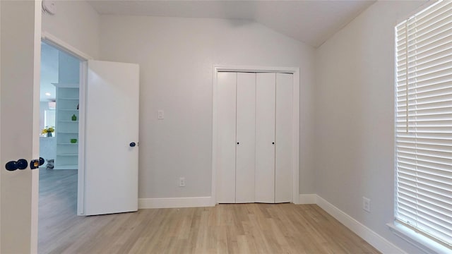 unfurnished bedroom with a closet, lofted ceiling, and light hardwood / wood-style flooring