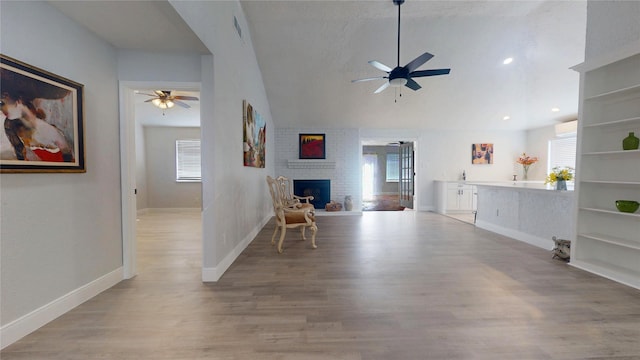 unfurnished living room featuring ceiling fan, a healthy amount of sunlight, a fireplace, and light hardwood / wood-style floors