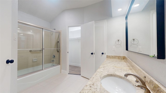 bathroom with enclosed tub / shower combo, vaulted ceiling, and vanity