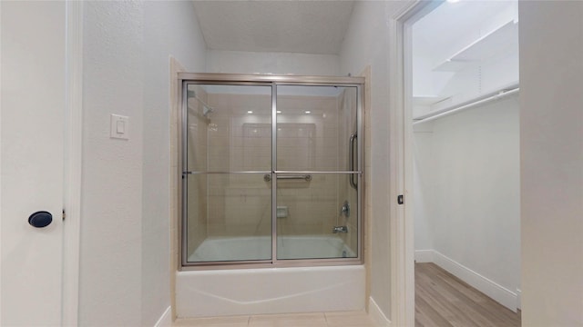 bathroom with enclosed tub / shower combo, wood-type flooring, and a textured ceiling