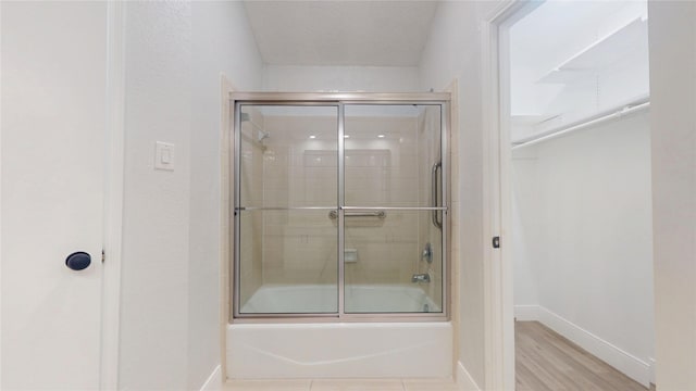 bathroom featuring hardwood / wood-style flooring and combined bath / shower with glass door