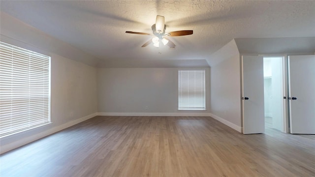 additional living space with ceiling fan, light hardwood / wood-style flooring, and a textured ceiling