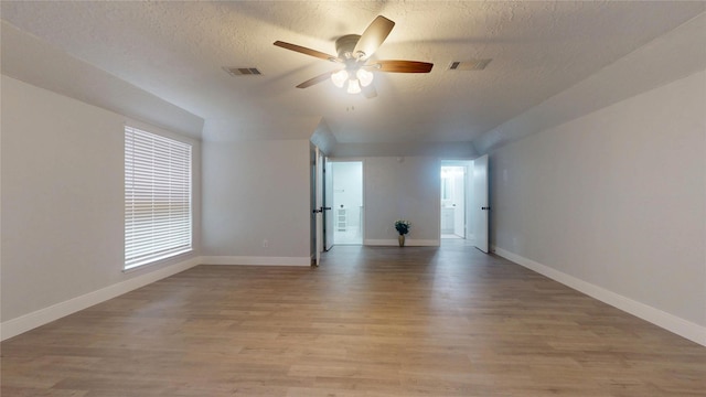 spare room with ceiling fan, a textured ceiling, and light wood-type flooring