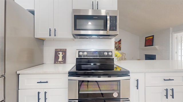 kitchen featuring white cabinetry, light stone countertops, tasteful backsplash, and stainless steel appliances