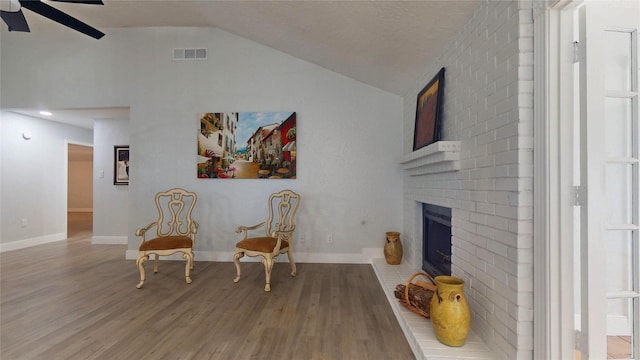 sitting room featuring ceiling fan, lofted ceiling, hardwood / wood-style floors, and a fireplace