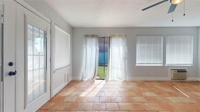 interior space with a wall mounted air conditioner, a wealth of natural light, a textured ceiling, and ceiling fan