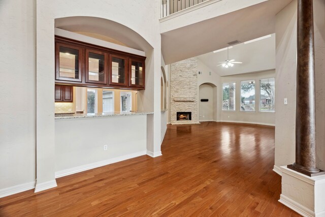 unfurnished living room with hardwood / wood-style flooring, ceiling fan, high vaulted ceiling, and a fireplace