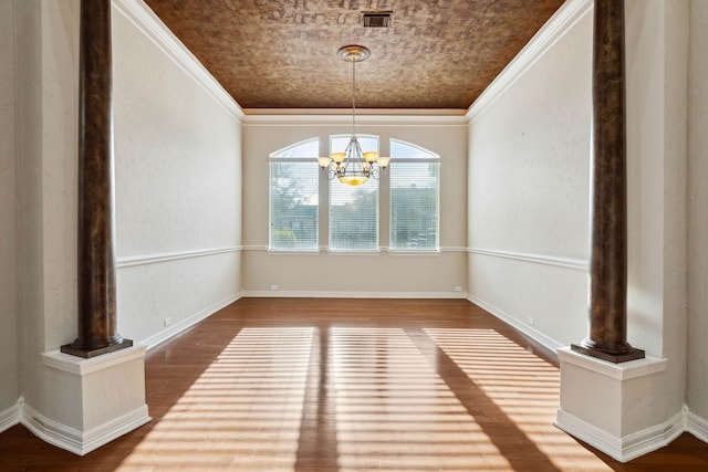 unfurnished dining area with ornamental molding, wood-type flooring, decorative columns, and a notable chandelier