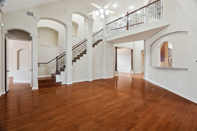 interior space featuring hardwood / wood-style flooring, a towering ceiling, ceiling fan, and ornate columns